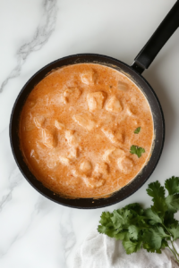 This image shows chicken simmering in the creamy sauce