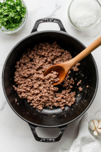 This image shows ground meat cooking in a large pot, broken into small pieces for Keto Crockpot Goulash