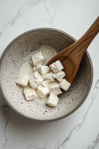 This image shows cream cheese being whisked into the sauce until smooth.