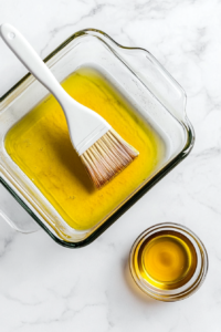 This image shows a baking dish being prepared with a light coat of grease.