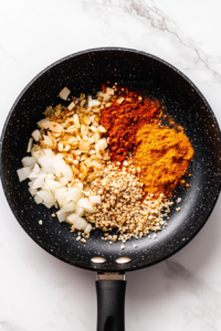 This image shows garlic, ginger, and spices being stirred together