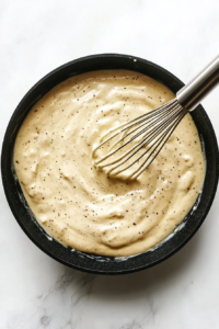 This image shows Alfredo sauce being whisked in the skillet until smooth and creamy.