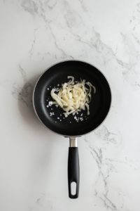 This image shows onions being sautéed with kosher salt in the pan.
