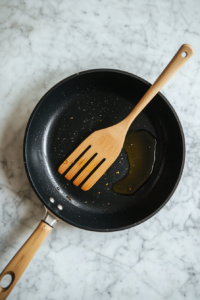 This image shows olive oil being heated in a skillet on medium heat, creating the base for cooking vegetables and shrimp.
