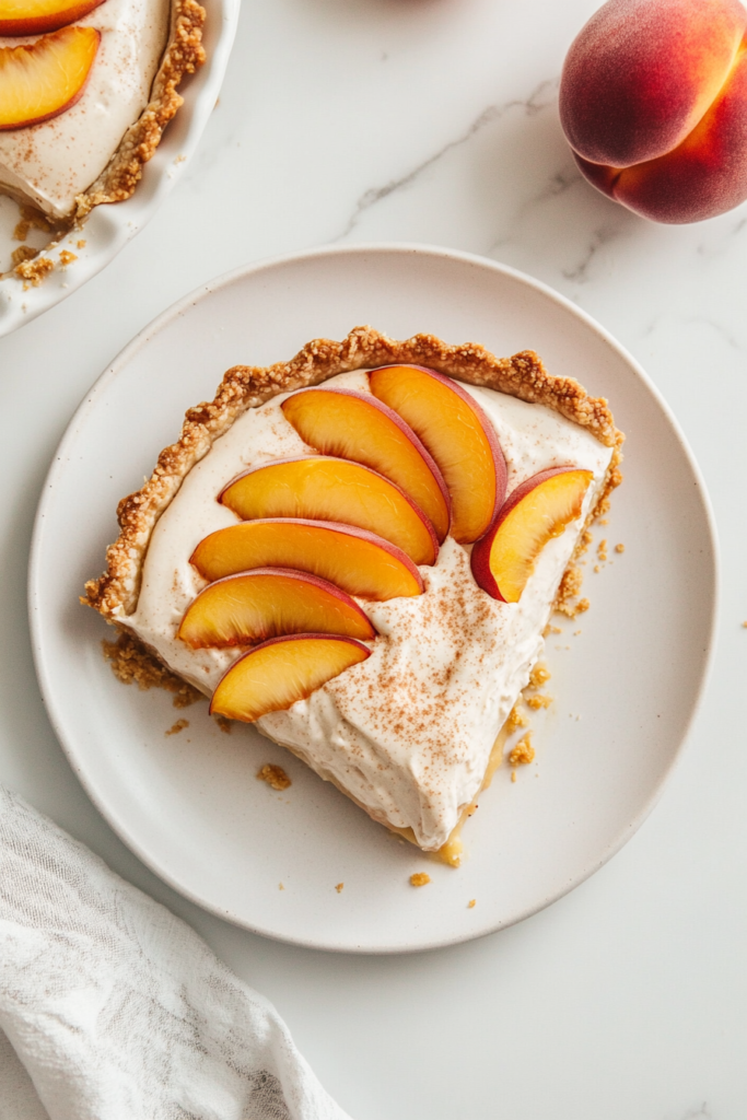 this image shows delightful vegan peach cream pie featuring a golden-brown crust, a creamy filling, and perfectly arranged fresh peach slices as a garnish.
