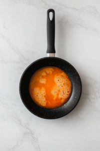 This image shows a pan of sauce simmering gently over medium heat, with small bubbles forming as the mixture thickens to a rich and velvety consistency over 10 minutes.