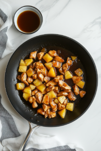 This image shows the sauce being stirred and adjusted in the skillet to achieve the perfect consistency before serving the chicken teriyaki pineapple bowls.