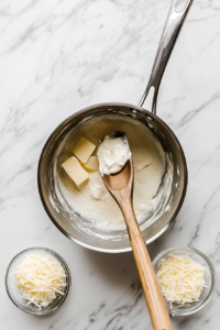 This image shows the Alfredo sauce gently simmering, thickening to a velvety consistency, ready to coat the stuffed shells.