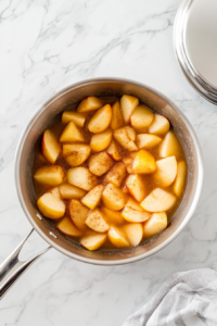 This image shows apples gently cooking in a pot, releasing their natural sweetness and breaking down into a soft, fragrant mixture.