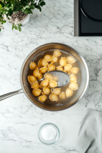 This image shows large pasta shells boiling in a pot of salted water, softening to the perfect texture for stuffing.