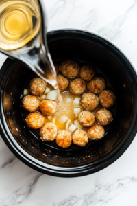This image shows chopped onions, minced garlic, white wine, and broth being poured into the slow cooker for depth of flavor.