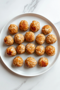 This image shows hands gently rolling the seasoned chicken mixture into uniform meatballs, ensuring even cooking.
