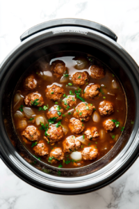 This image shows the slow cooker filled with meatballs and broth, gently simmering to perfection.