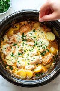 This image shows fresh chopped parsley being sprinkled over the Garlic Parmesan Chicken Potatoes, adding a burst of color and freshness to the dish.