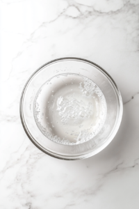 This image shows yeast proofing in a small bowl with warm water and sugar, bubbling up as it activates for the perfect Pizza Hut cheese sticks dough.