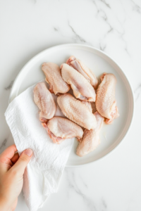 This image shows raw chicken wings on a cutting board, prepared for seasoning and cooking.