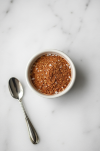 This image shows a bowl filled with a blend of dry spices being mixed together to create a flavorful seasoning for the salmon bites.