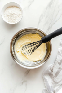 This image shows milk being whisked into the butter and flour mixture, creating a smooth and creamy base for the cheese sauce.