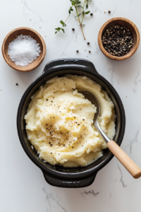 This image shows salt and black pepper being sprinkled over the mashed potatoes, enhancing their flavor.