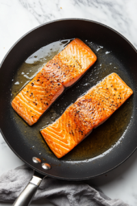 This image shows the perfectly seared salmon resting on a plate while the sauce is prepared.