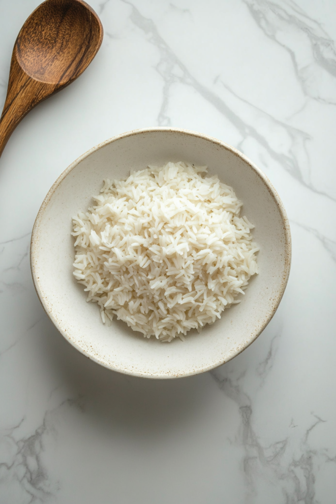 After resting, the Bomba rice is gently fluffed with a fork, allowing the grains to separate and create a light, airy texture, ready for serving.
