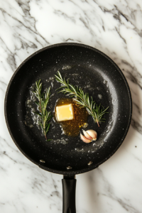 This image shows a skillet with melted butter, oil, and fresh herbs sizzling together. The herbs infuse the oil with flavor, making the potatoes extra delicious.