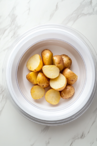 This image shows a bowl of quartered potatoes being microwaved to partially cook them. This step helps speed up the frying process while keeping the inside fluffy.