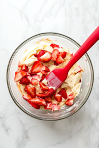 This image shows the crumble topping being sprinkled over the unbaked strawberry rhubarb bread batter, ready to add texture and flavor.