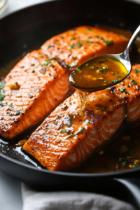 This image shows the seared salmon fillet being returned to the pan, soaking up the delicious soy-based sauce.