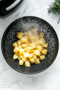 This image shows a potato masher pressing into soft, cooked potatoes, creating a smooth and fluffy texture.