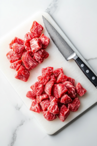This image shows fresh strawberries being carefully chopped on a wooden cutting board, ready to be added to the punch for a burst of fruity flavor.