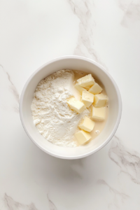 This image shows flour, salt, oil, and butter blending together in a food processor to form the base of a tender tart dough.