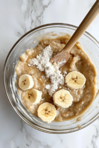 This image shows the dry ingredients being gently folded into the wet mixture using a rubber spatula, then half the batter being spread into the prepared baking pan.