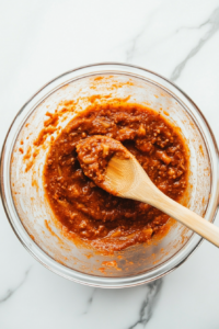This image shows the cooked pasta being gently stirred into the cheesy mixture until well coated.