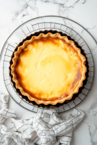 This image shows smooth custard being gently poured over the arranged apple slices inside the tart shell.