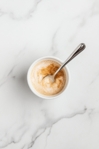 This image shows an even layer of cinnamon sugar being sprinkled on top of the first layer of batter.