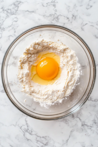 egg-added-to-biscuit-dough-in-glass-bowl