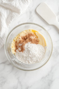 mixing-flour-and-spices-into-batter-in-clear-glass-bowl