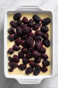 pouring-batter-over-blackberries-in-white-baking-dish