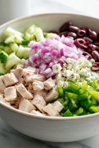 Add the cooked chicken, diced cucumber, celery, red onion, feta cheese, and olives if using.